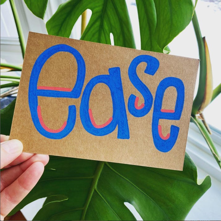 photo of my hand holding a craft paper postcard in front of a monstera leaf. on the postcard is the word "ease" hand lettered in blue with red accents