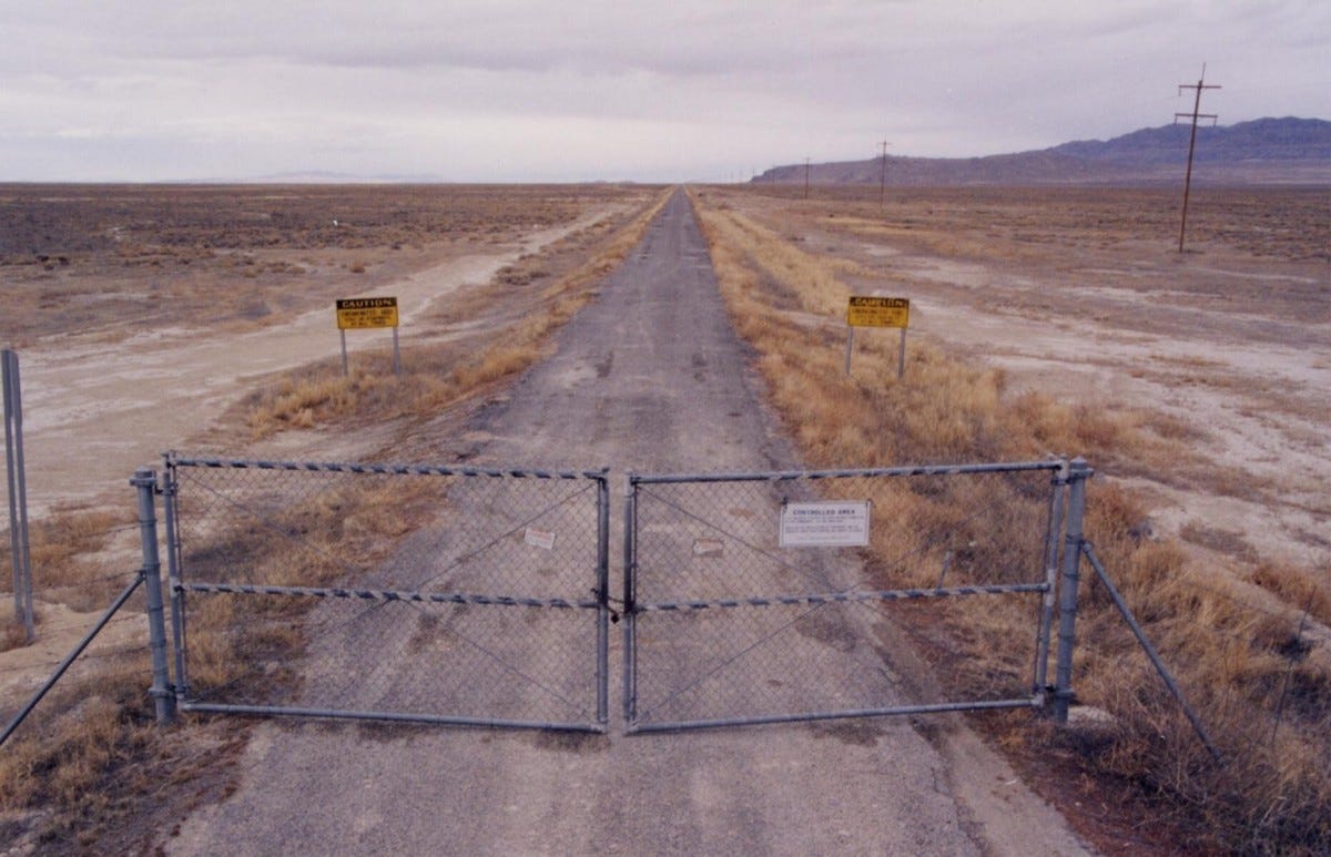 Photo of gate crossing a beat up asphalt road at the Utah Test and Training Range Photo of gate crossing a beat up asphalt road at the Utah Test and Training Range
