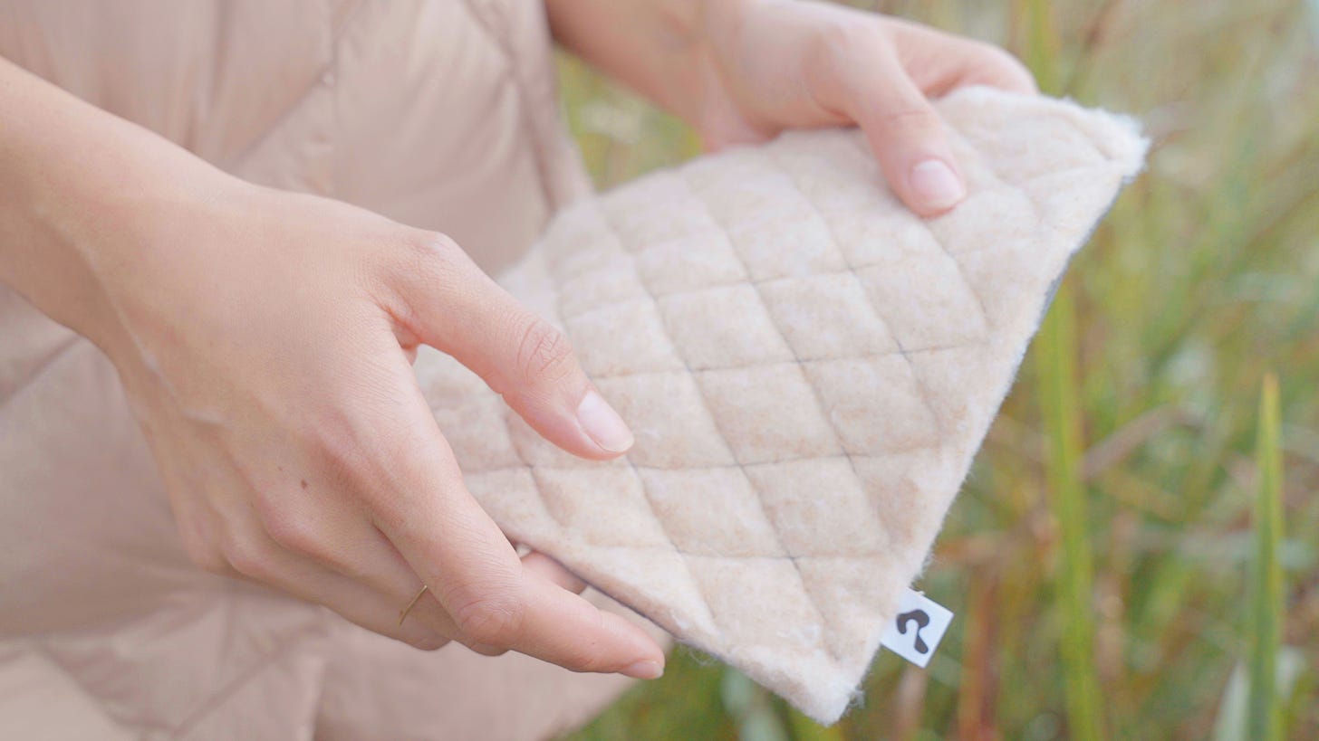 close up to the hands of a person supporting a sample of biopuff material 