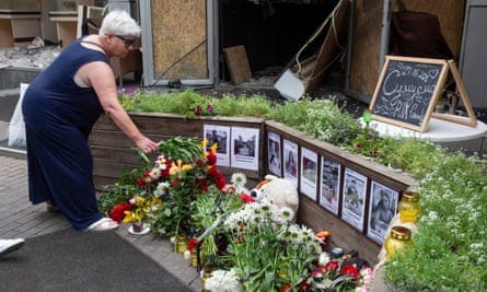 A woman lays flowers at a makeshift memorial for the victims of the Russian missile strike on the Ria pizza restaurant in Kramatorsk, Ukraine.