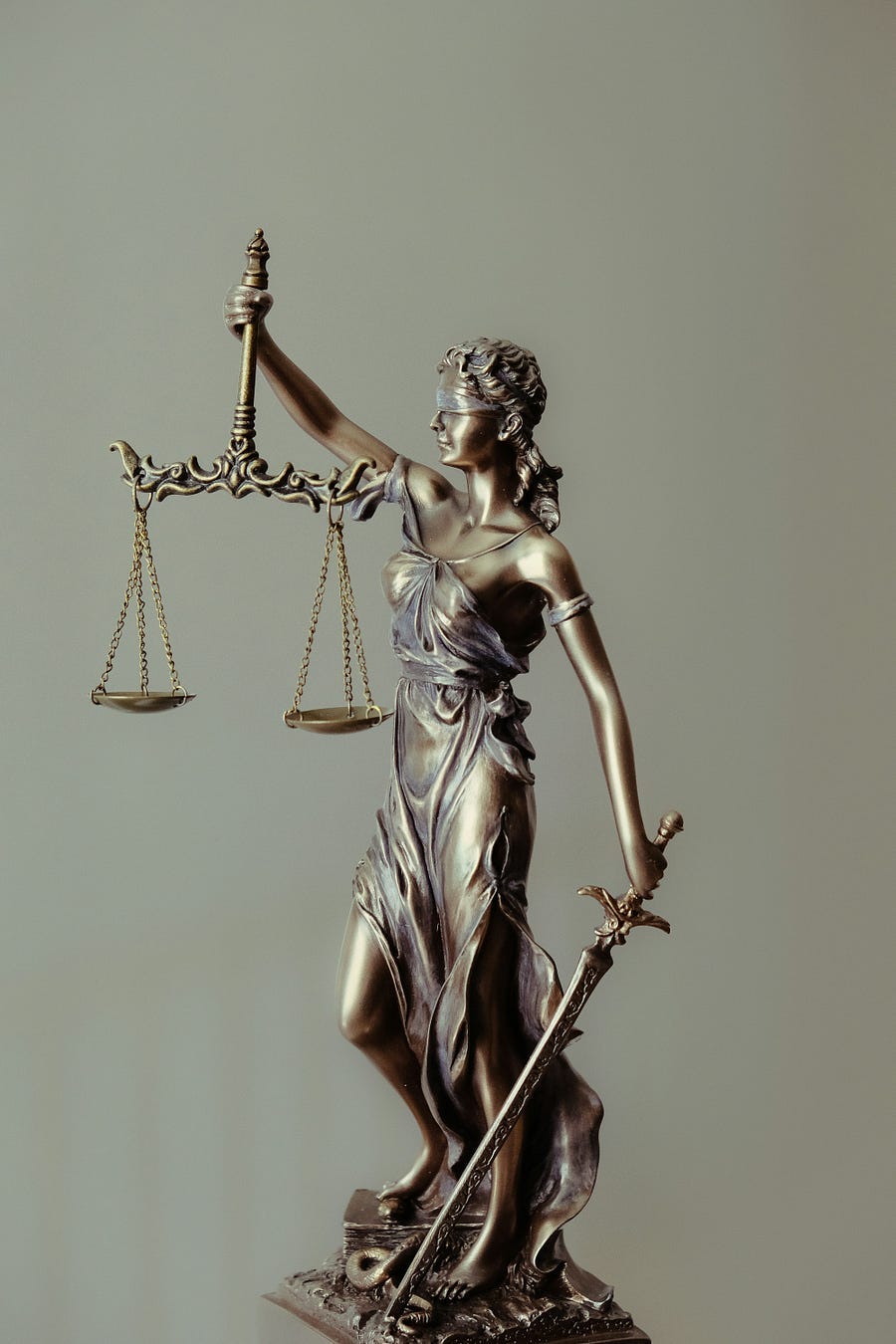 Statue of a blindfolded woman in silver holding the scales of justice. Statue of a blindfolded woman in silver holding the scales of justice.