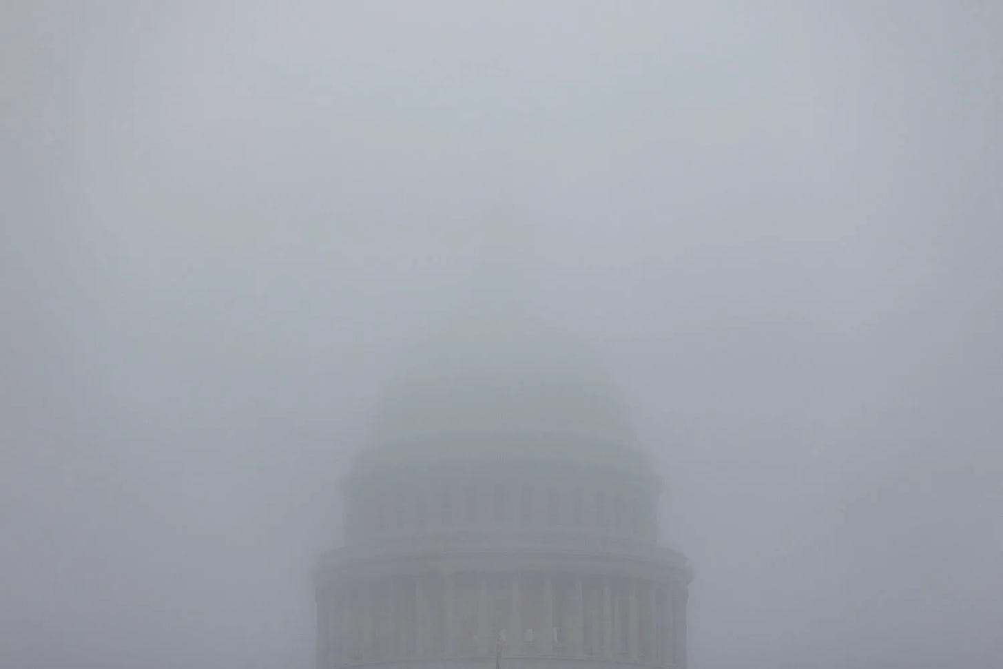 Fog hides most of the top of the Capitol dome.