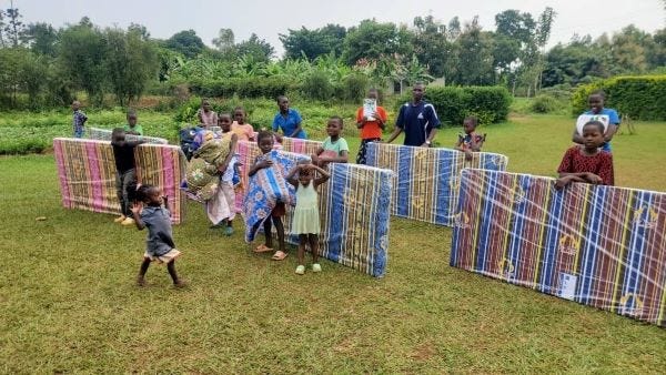 a group of children posed with plastic-wrapped mattresses and blankets