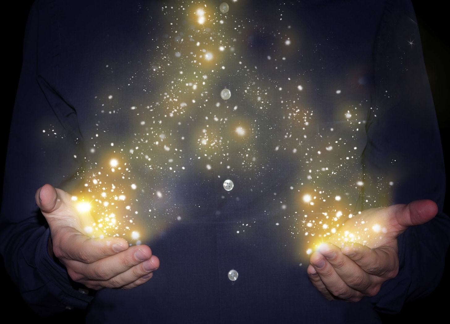 a man's hands with sparkles rising between them