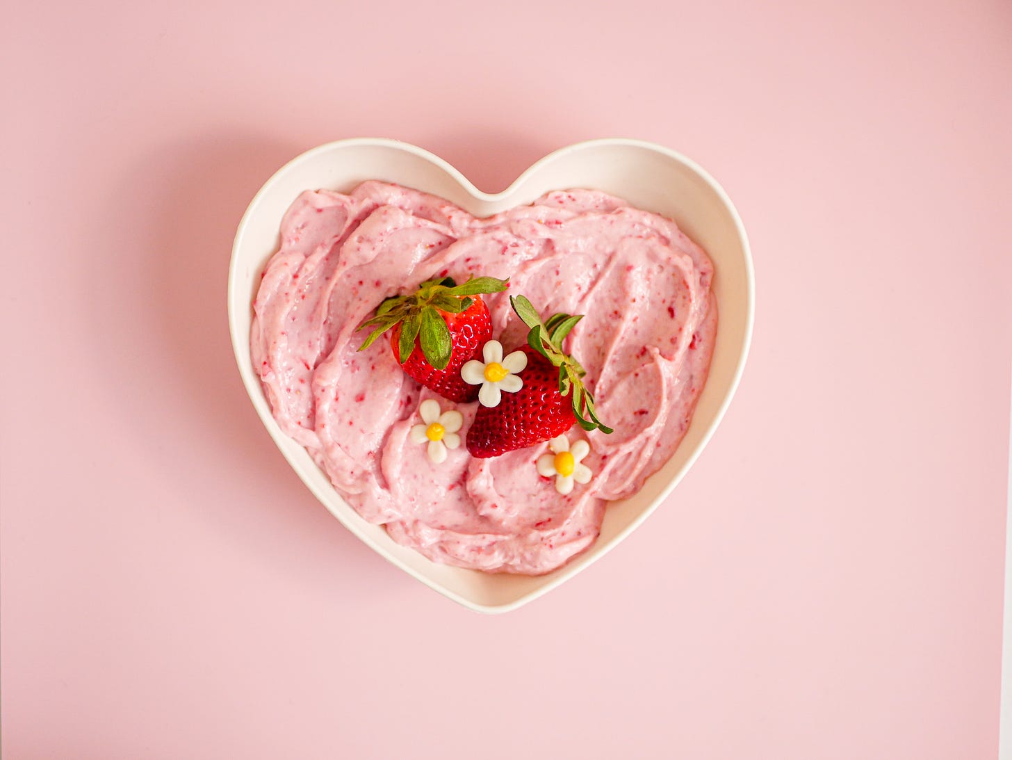 strawberry yogurt frosting with fresh strawberries in a white heart dish and pink background