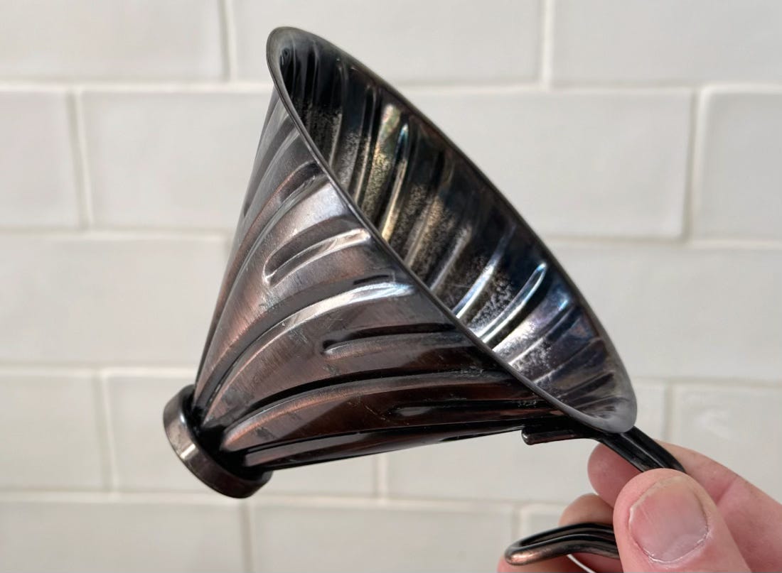 A metal cone is held in front of some tiles