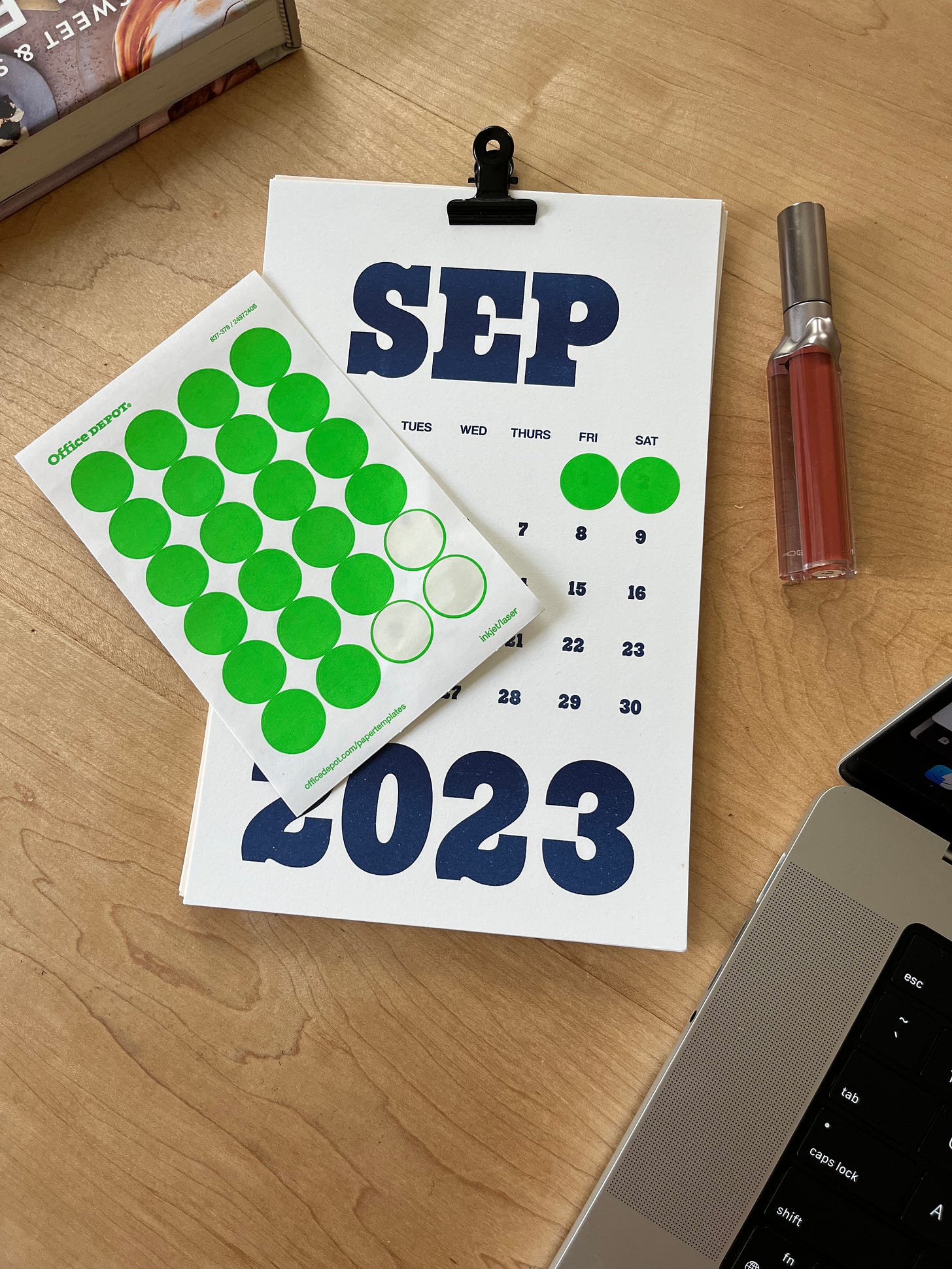 A September 2023 calendar page with a sheet of neon green circle stickers next to it.