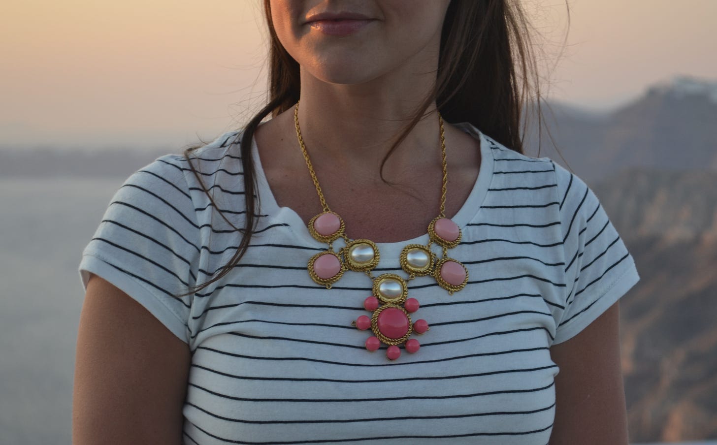 Photo of woman in a striped T-shirt and a truly heinous pink Kendra Scott necklace that resembles a chemical compound or perhaps an outbreak of warts.