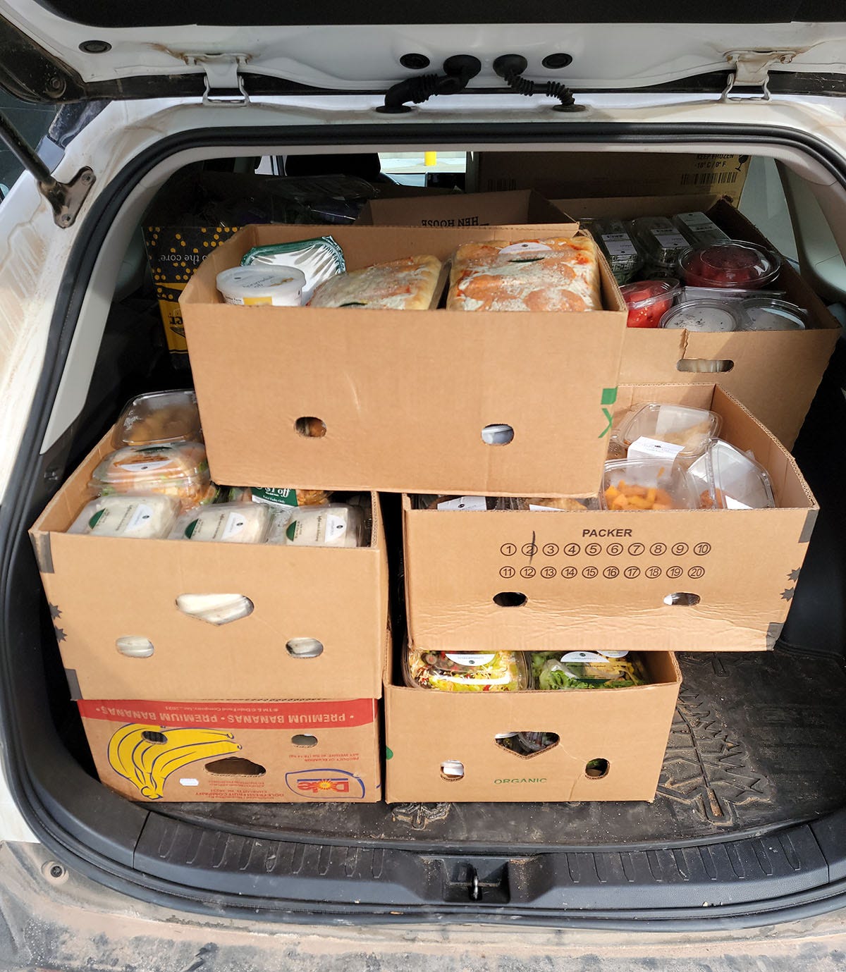 Boxes of food from a supermarket loaded into the back of a car. 