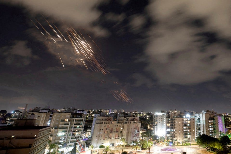 Iron Dome anti-missile system intercepting rockets over a city at night.