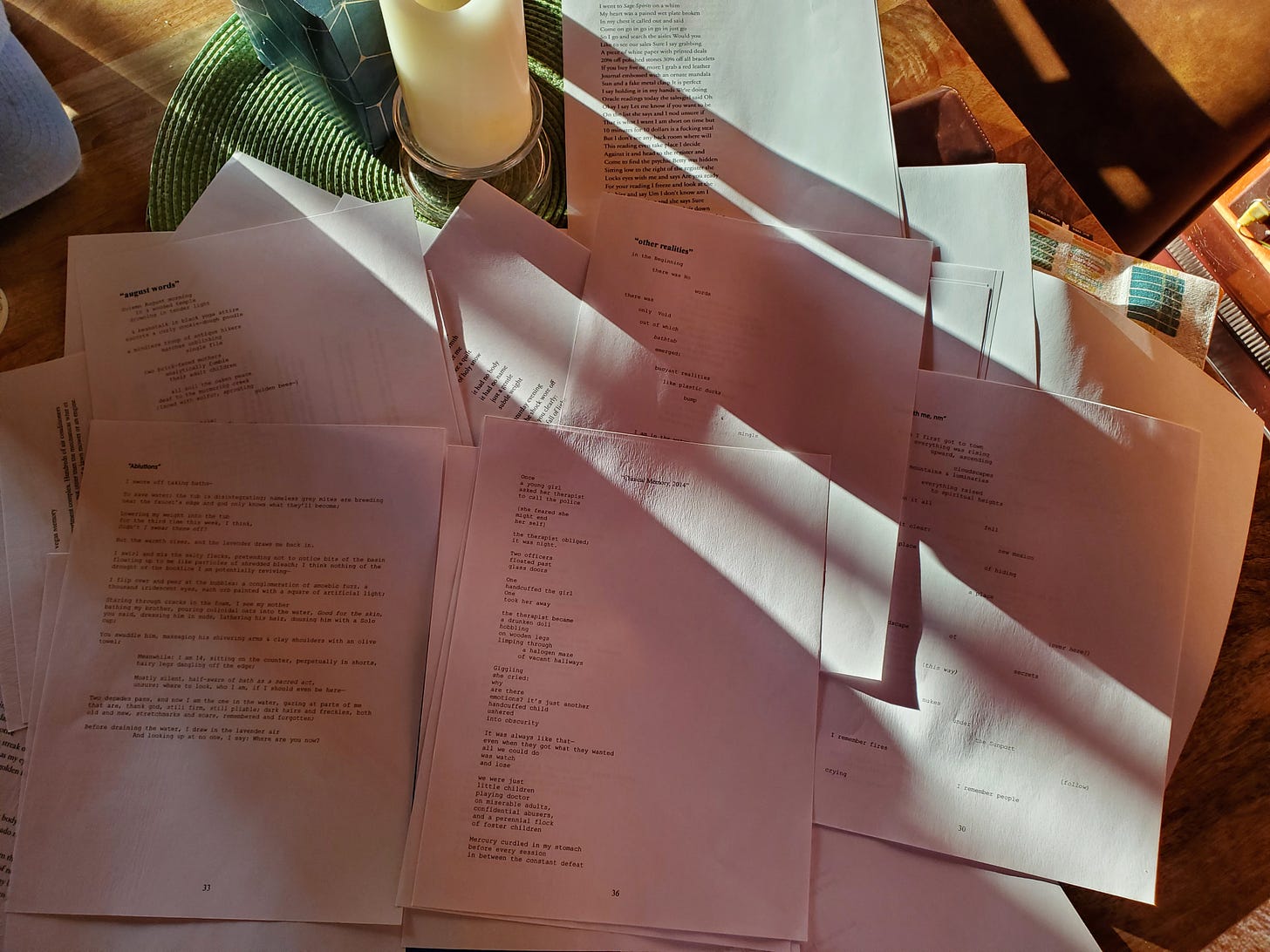 A pile of printed pages covered in poetic text lays on a kitchen table. Shafts of sunlight and shadow run across the surface. The poems themselves are illegible from this distance.