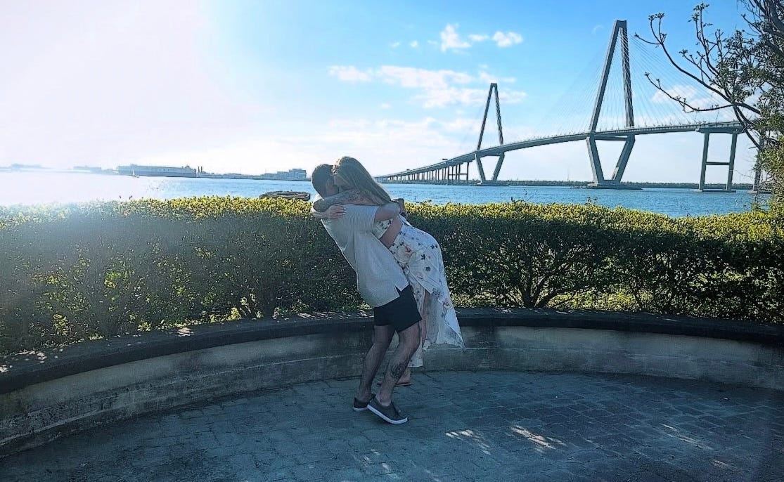 couple hugging in front of a bridge