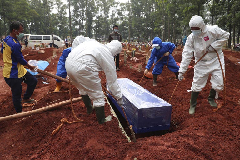 FILE - Workers in protective gear lower a coffin of a COVID-19 victim to a grave for burial at the Cipenjo Cemetery in Bogor, West Java, Indonesia, Wednesday, July 14, 2021. The World Health Organization says member countries on Saturday, June 1, 2024, approved a series of new steps to improve global preparedness for and response to pandemics like COVID-19 and mpox. (AP Photo/Achmad Ibrahim, File)