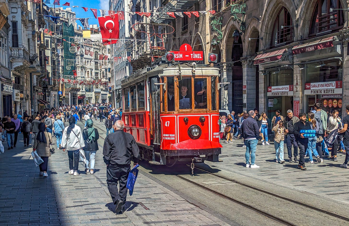 The bright red tram running down a busy Istiklal Street. 