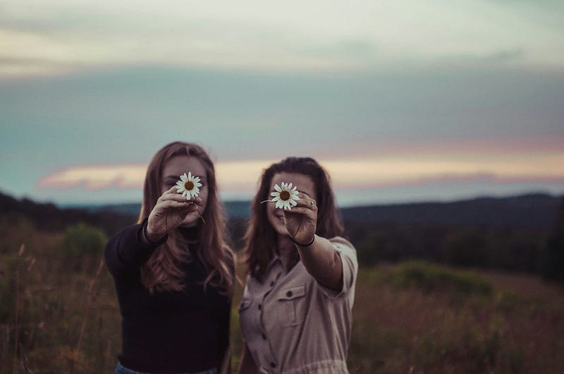 two friends hold a flower each. two friends hold a flower each.