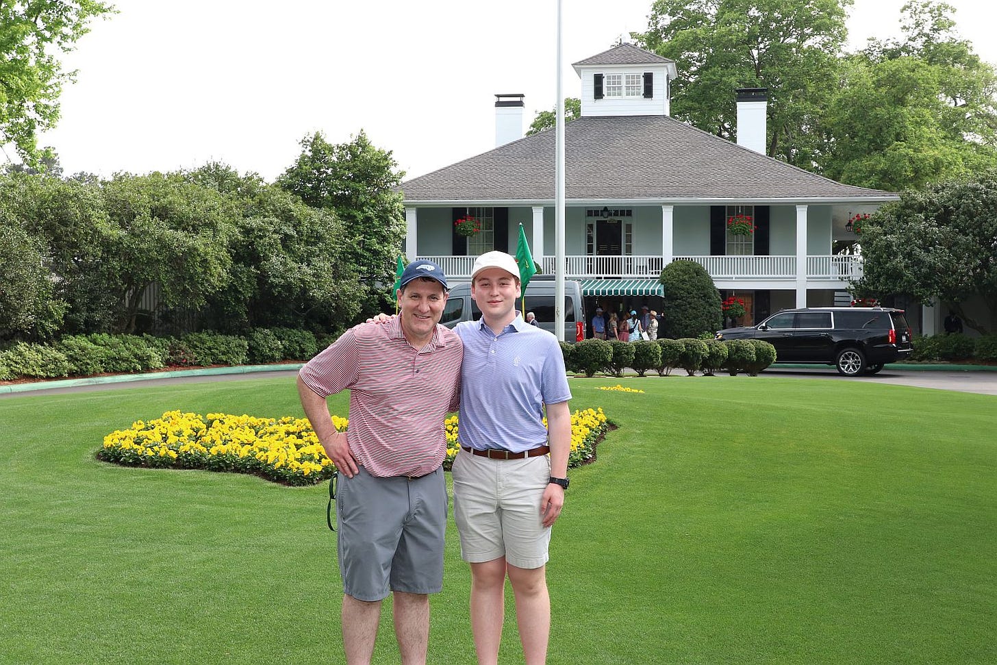 The author, on the right in a blue polo, and his father, on the left in a red polo, stand in front of the famous clubhouse at the Augusta National Golf Club.