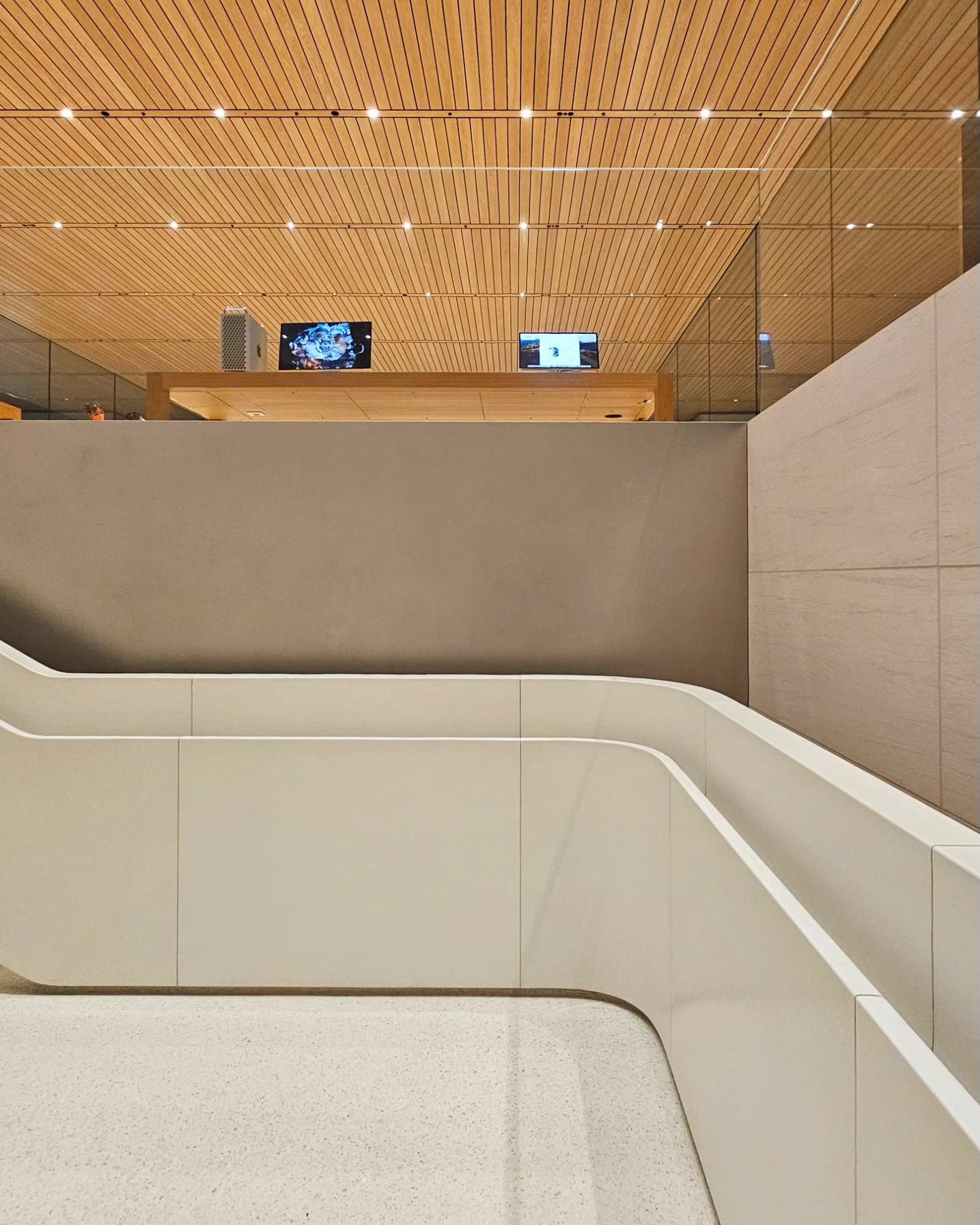 The interior of Apple Xinyi A13, photographed from midway between the ground level and basement level. Above the floor peeks a product display table.