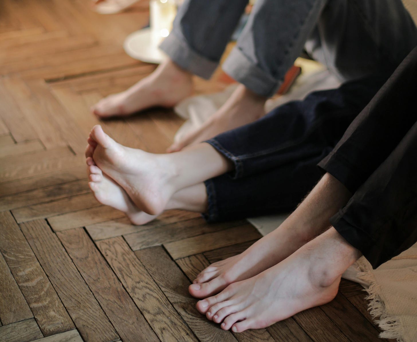 three pairs of feet on a wooden floor