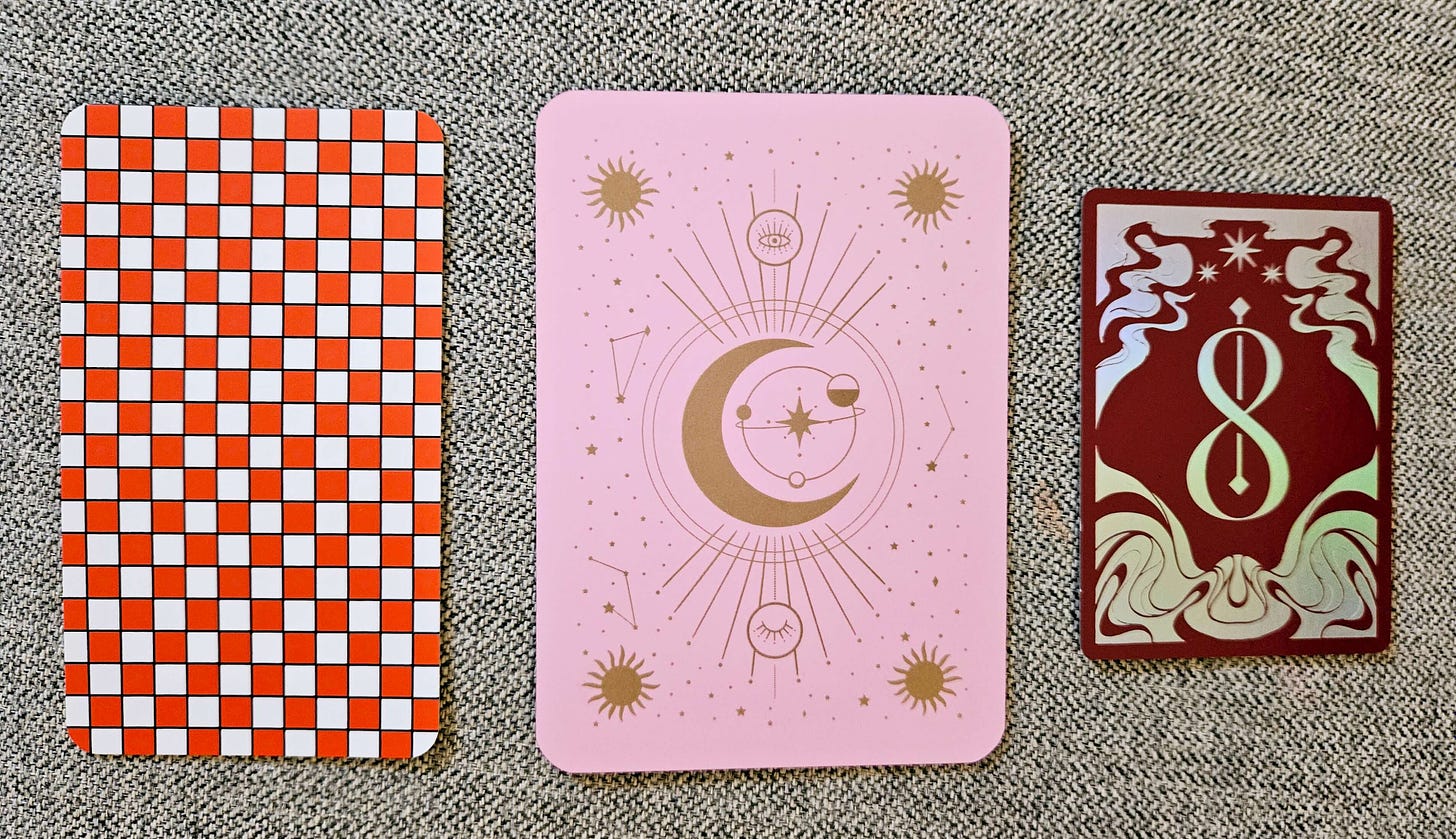 Three cards to choose one from for new year inspiration: one with a red and white checked background, one pink with a gold moon and stars background, and one burgundy with a gold swirling border and the number 8 pierced by an arrow and a star at the top.