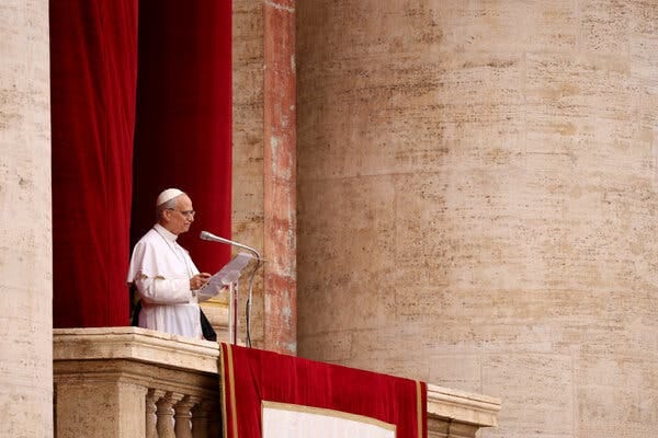 The pope, dressed in white, speaks from a balcony in front of crimson red curtains. The pope, dressed in white, speaks from a balcony in front of crimson red curtains.