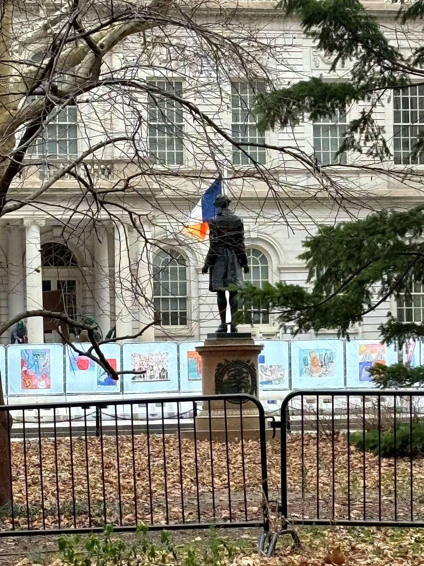 The back of Hale's statue, facing city hall and the New York flag. It is protected by a fence.
