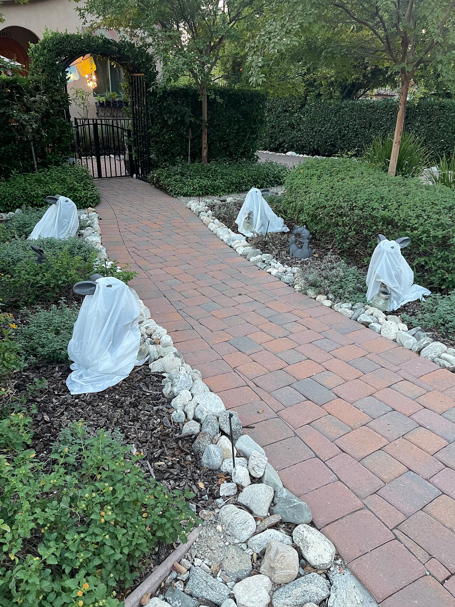 Brick entryway path lined with stone bunny rabbits dressed in ghost halloween costumes