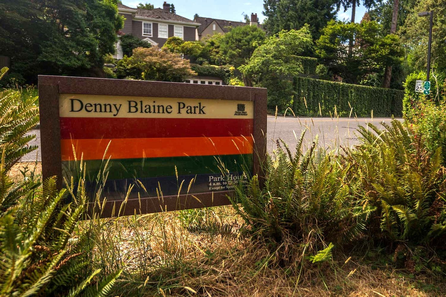 The park signage at Denny Blaine Park with wealthy homes visible in the background. 