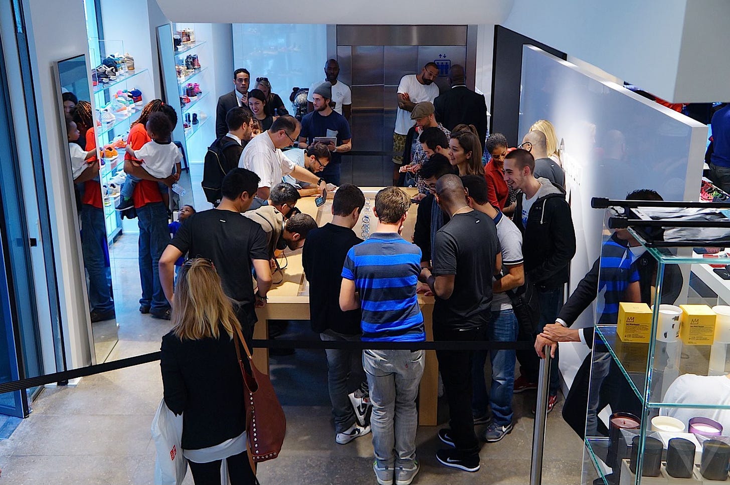 Customers gather around the glass Apple Watch display table at Colette in Paris.