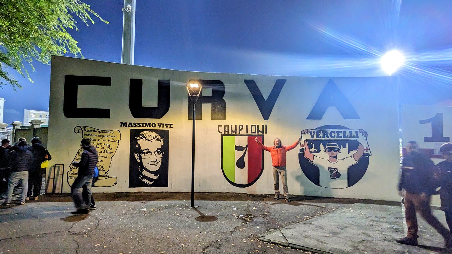 A man stands in front of a wall of a football stadium. There are images of the club and the writing "curva" on the wall to symbolise the home end of the fans