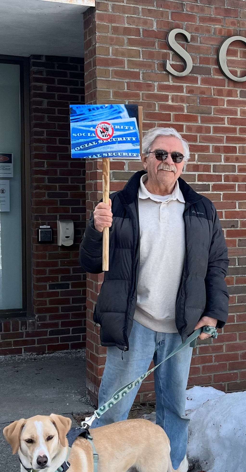 A man holding a sign that reads Hands Off Social Security in front of a brick building with "Social Security" on the front. He has a dog on a leash. List subscriber Chuck D and pup making their voices heard at their local Social Security office. Let’s join them! A man holding a sign that reads Hands Off Social Security in front of a brick building with "Social Security" on the front. He has a dog on a leash. List subscriber Chuck D and pup making their voices heard at their local Social Security office. Let’s join them!