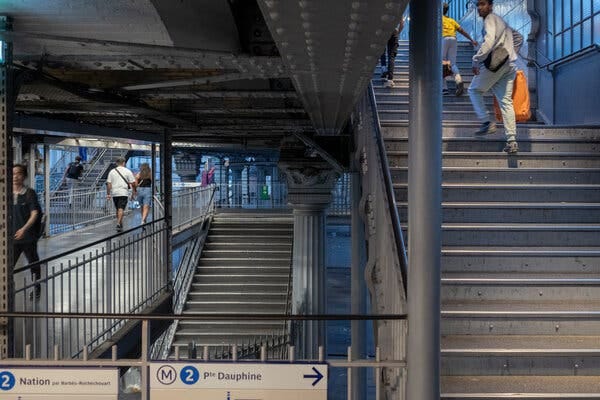 A view of the Paris Metro shows people walking up and down staircases.