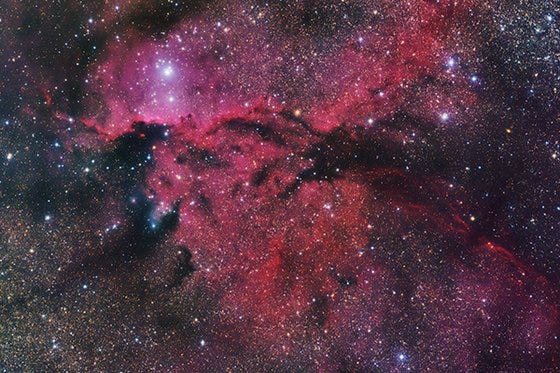 Cloud of air and dust in outer space which appears black and pink in the nightsky. 