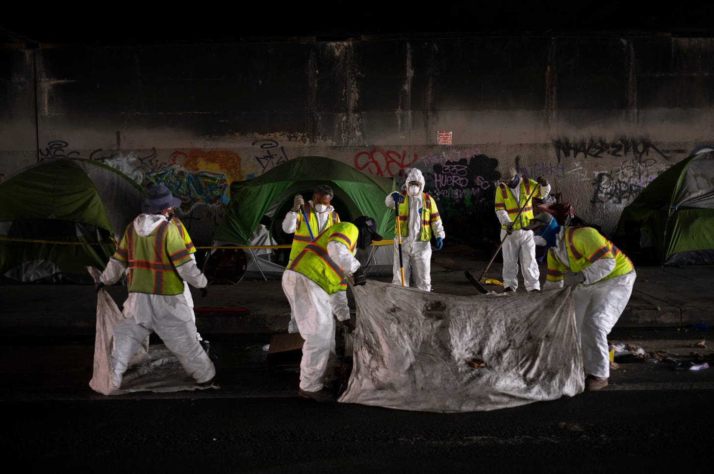 Los Angeles city employees clean up a homeless encampment to relocate homeless individuals into temporary housing.