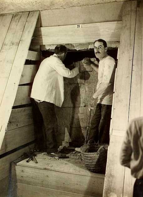 One of only two images showing Howard Carter (on the left) and Lord Carnarvon together in the tomb. They are beginning the process of dismantling the wall between the Antechamber and the Burial Chamber. (Public Domain)