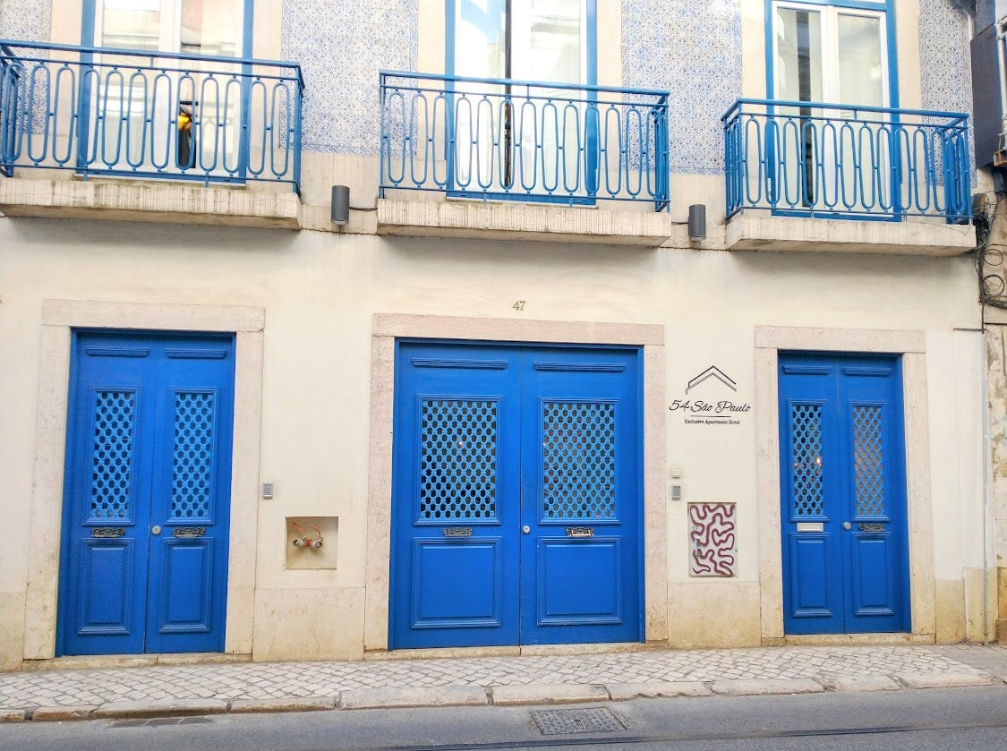 A typical Lisbon building with bright blue doors and colorful blue and white ceramic tiles on the facade.