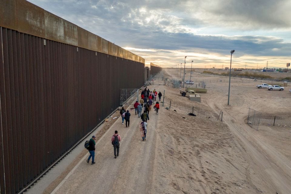 Aerial view of immigrants walking along the U.S.-Mexico border wall in El Paso, Texas.