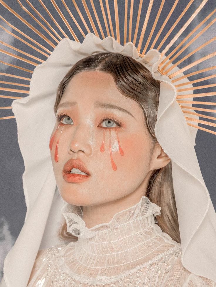 an Asian Mother Mary with a halo and red tears streaking down her face