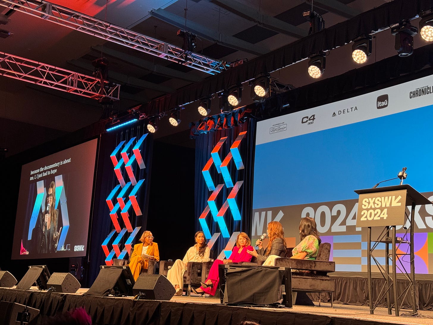 SXSW panel featuring (from left) Errin Haines, Meghan Markle, Katie Couric, Brooke Shields, and Nancy Wang Yuen. All sit in armchairs onstage with a colorful "SXSW 2024" marquee behind them.