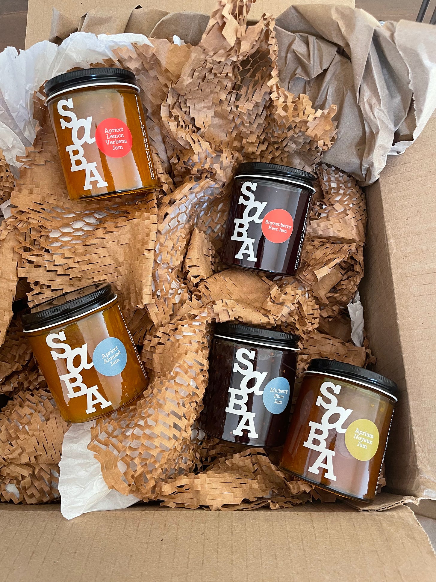 Box of Saba jam jars sitting atop wrapping materials