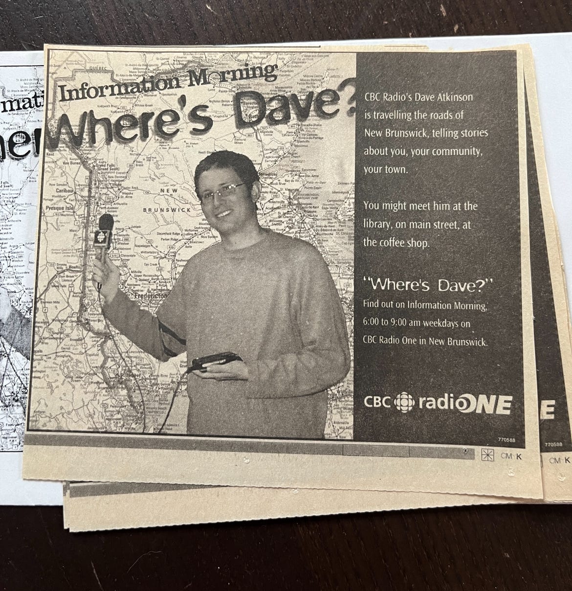 An old newspaper ad. There's a photo of a much younger me holding a microphone standing in front of a map of New Brunswick. The headline reads: Information Morning: Where's Dave? You might meet him at the library, on main street, at the coffee shop. Where's Dave? Find out on Information Morning, 6-9 a.m. on weekdays on CBC Radio ONe in New Brunswick.