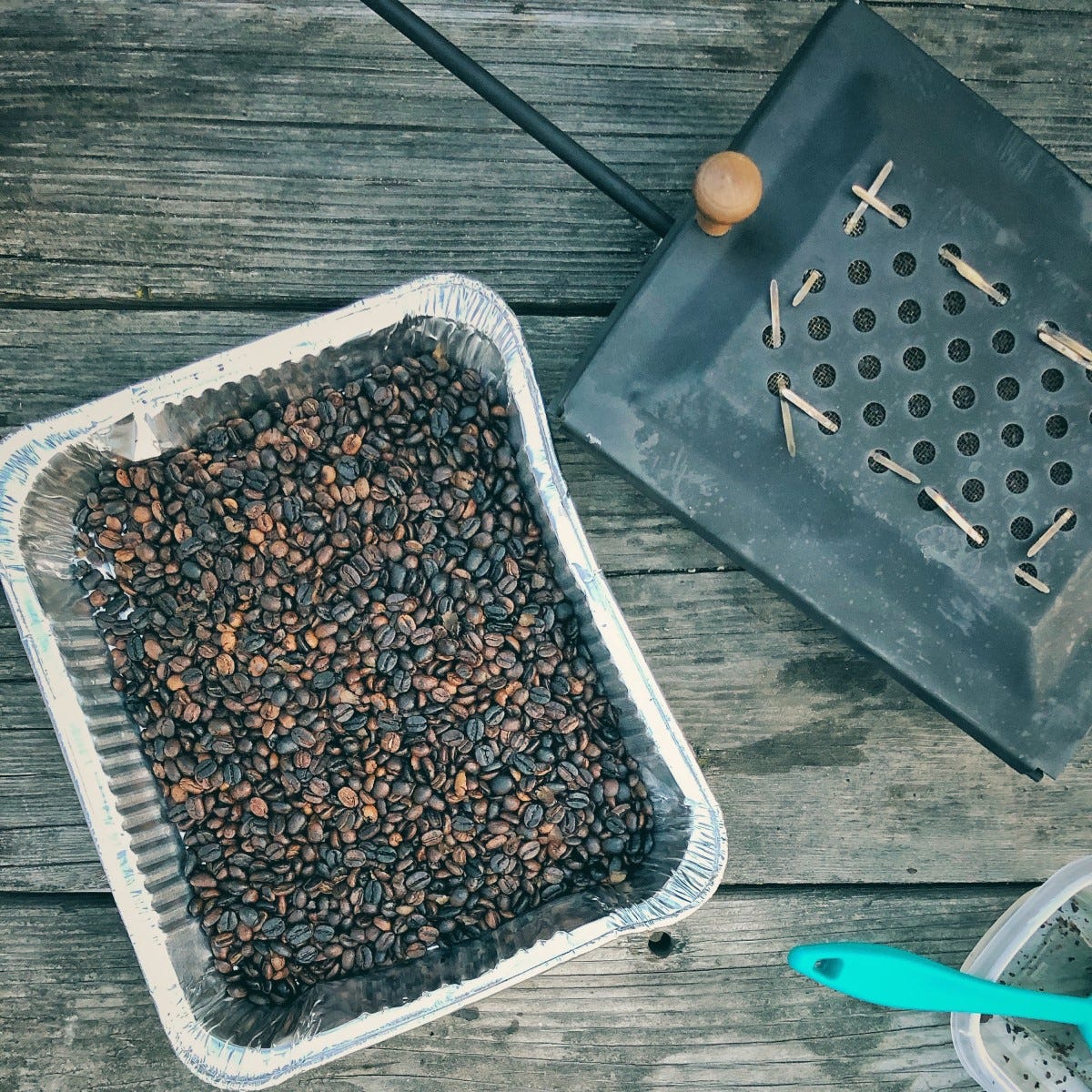 Campfire Coffee's original roaster, an adapted popcorn shaker seen from above next to some roasted coffee