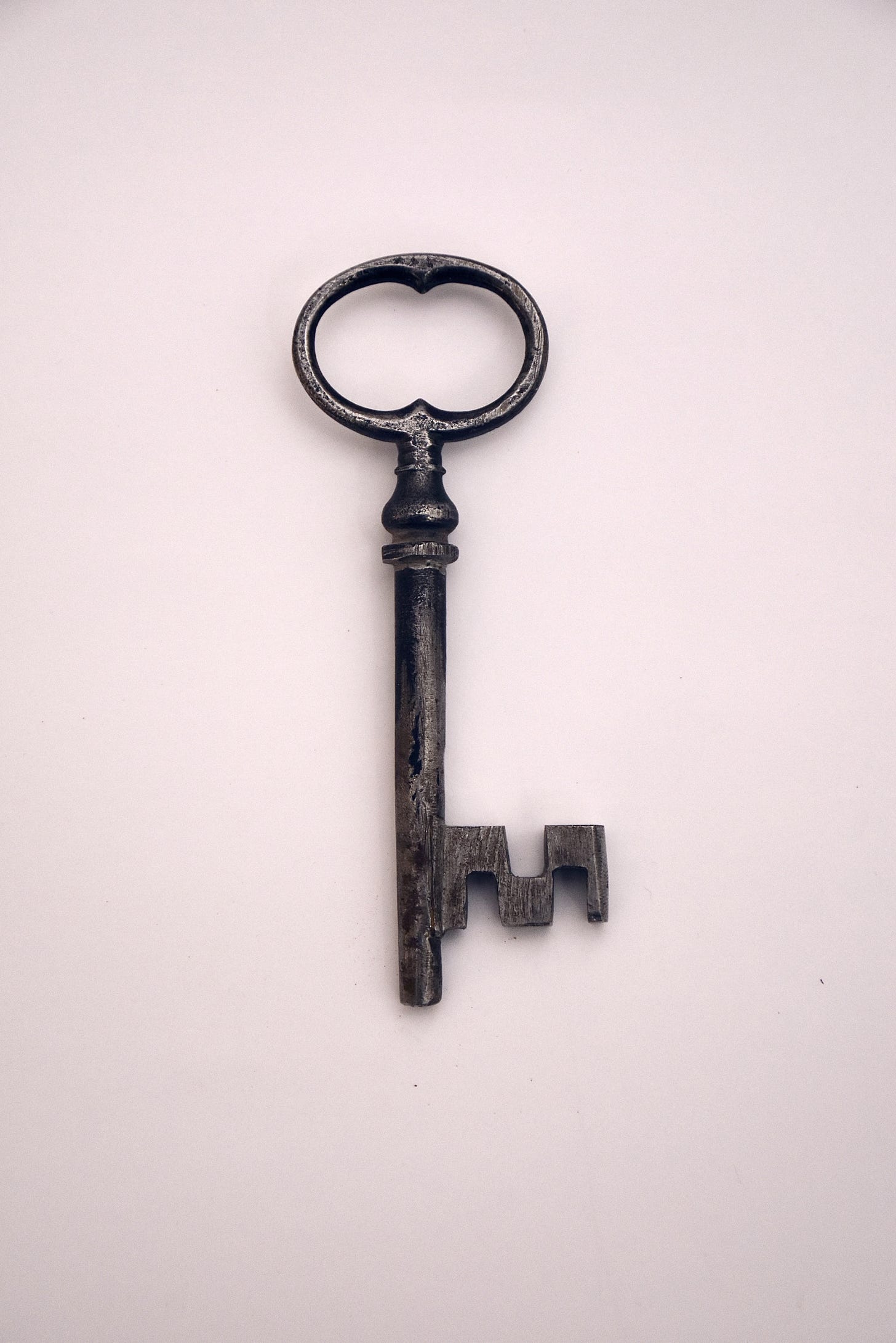 an old fashioned black key on a pink background