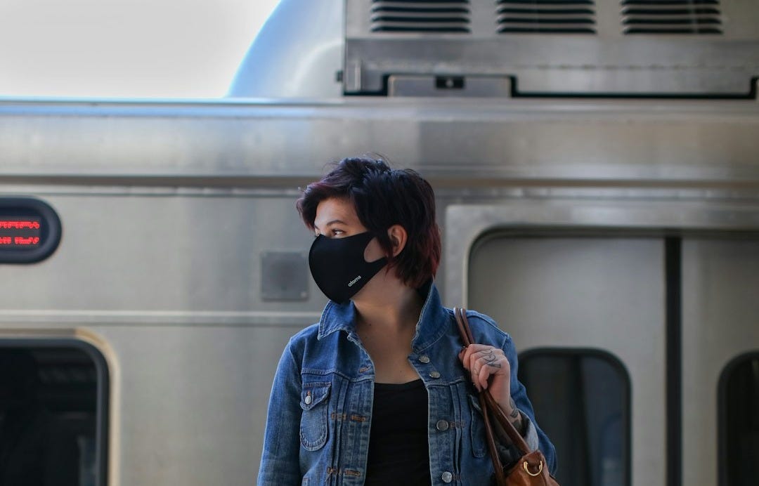 woman in blue denim jacket and black pants standing beside train