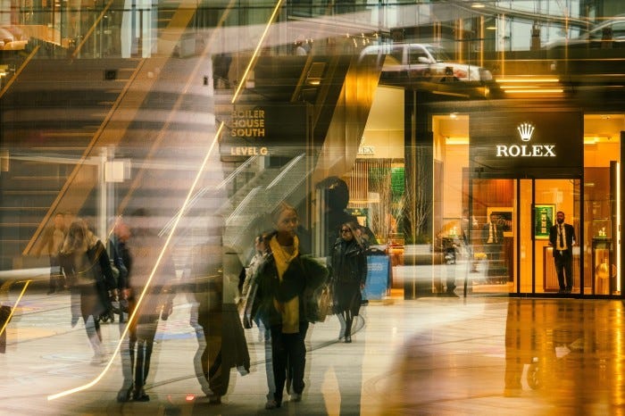 People walking inside a shopping mall with a Rolex store in view