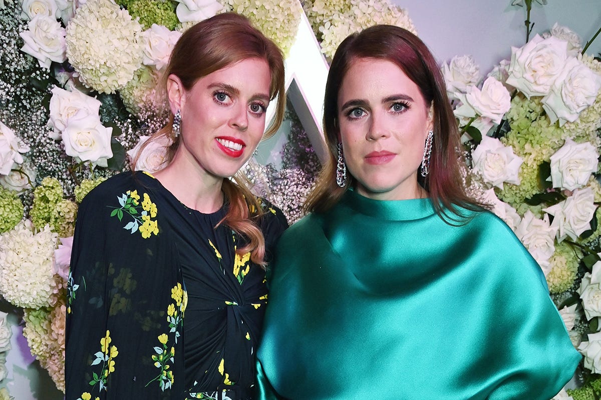 Princesses Beatrice and Eugenie wearing smart dresses and smiling for the camera