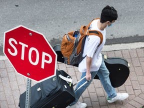 A man carrying a suitcase and guitar case.