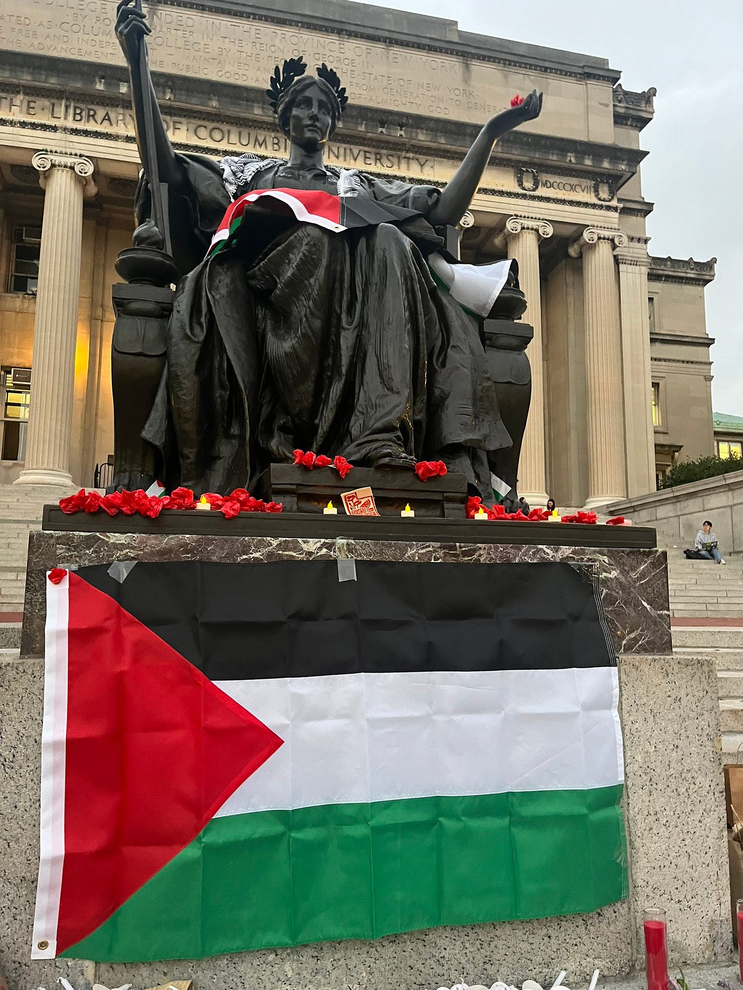 Columbia alma matter statue with poppies and prayer candles. Visible in the background is Low Library.