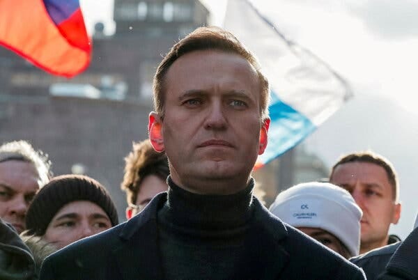 a photograph of Alexei Navalny standing outside amid a group of people.