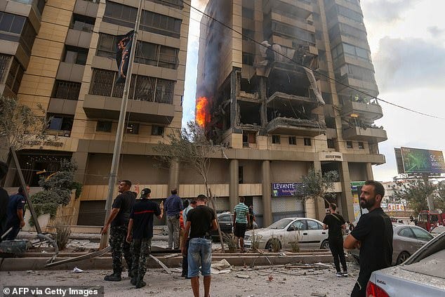 Lebanese civil defence and civilians stand at the scene of an Israeli airstrike that targeted an apartment building in south Beirut Jnah neighbourhood, on October 1, 2024