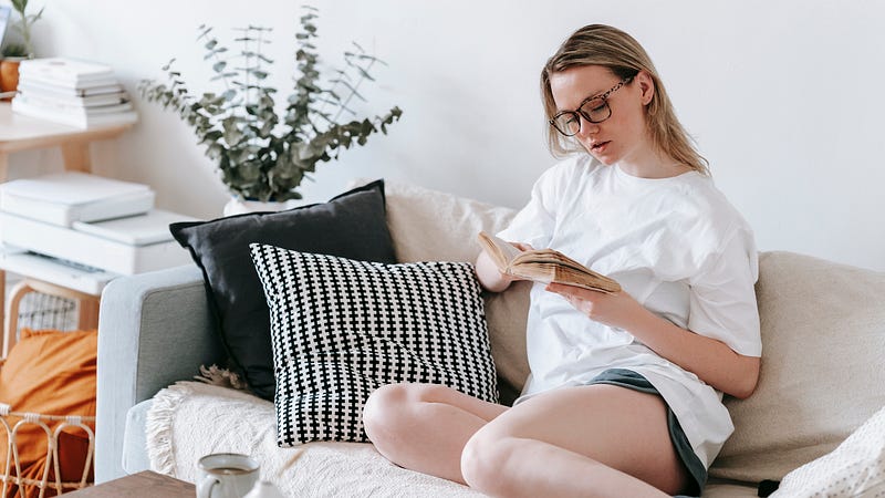 Focused woman reading book on sofa
